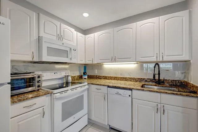 a kitchen with granite countertop white cabinets and white appliances