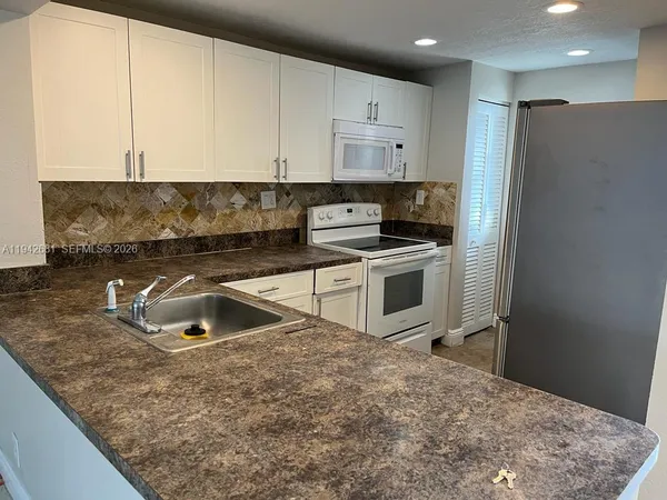 a kitchen with stainless steel appliances granite countertop a sink a stove and a refrigerator