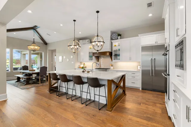 a large kitchen with stainless steel appliances kitchen island granite countertop a large kitchen island a refrigerator a stove and a sink