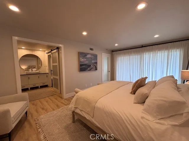 a bedroom with a bed a mirror on dresser and a window