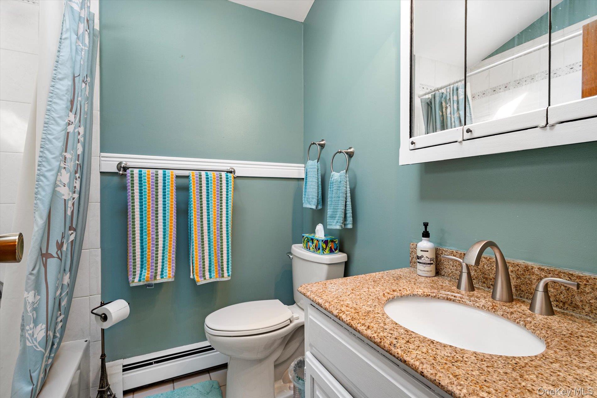 65 Harriet Road North Babylon, NY 11703 - Photo 17 of 31 Bathroom featuring baseboard heating, tile patterned flooring, vanity, shower / bath combination with curtain, and lofted ceiling