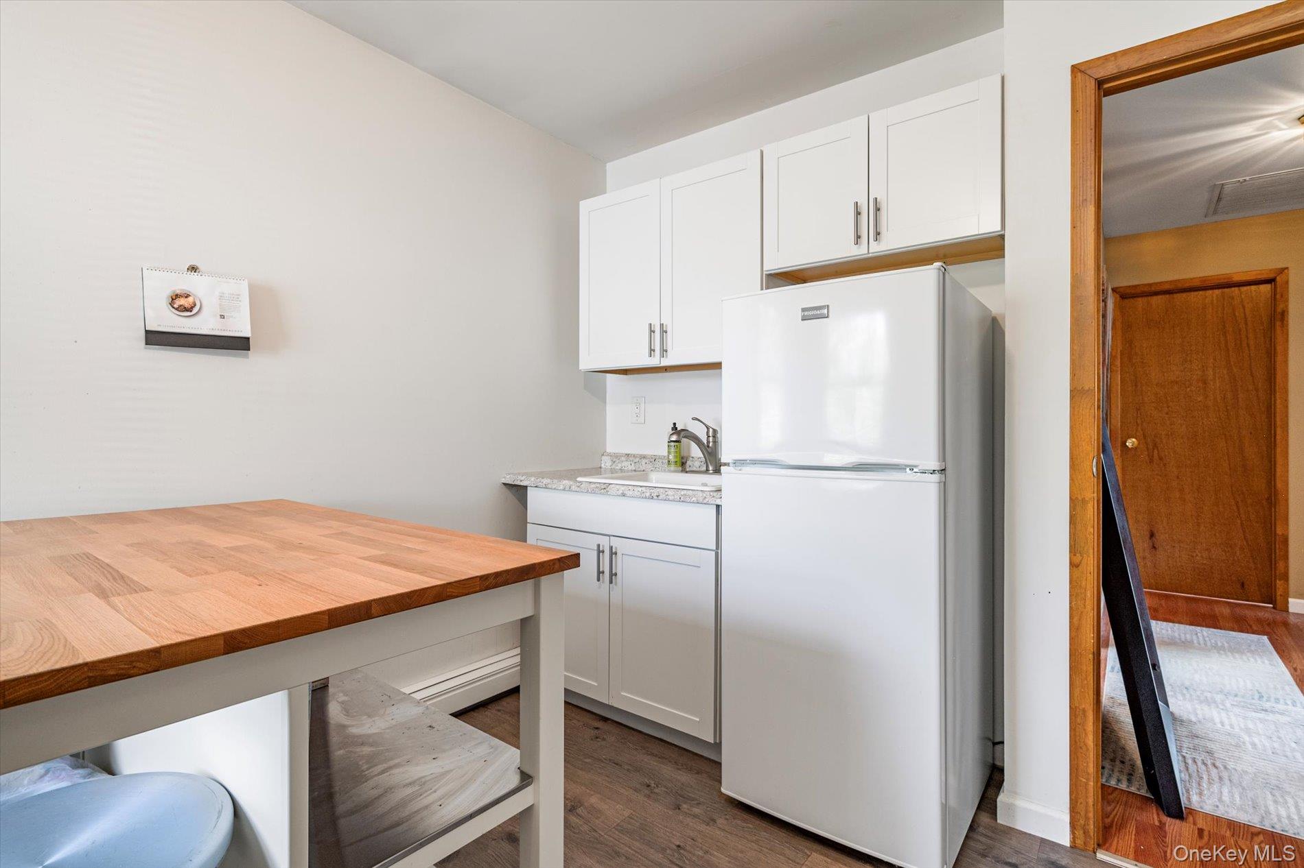 65 Harriet Road North Babylon, NY 11703 - Photo 19 of 31 Kitchen featuring butcher block counters, freestanding refrigerator, dark wood-style flooring, and white cabinetry