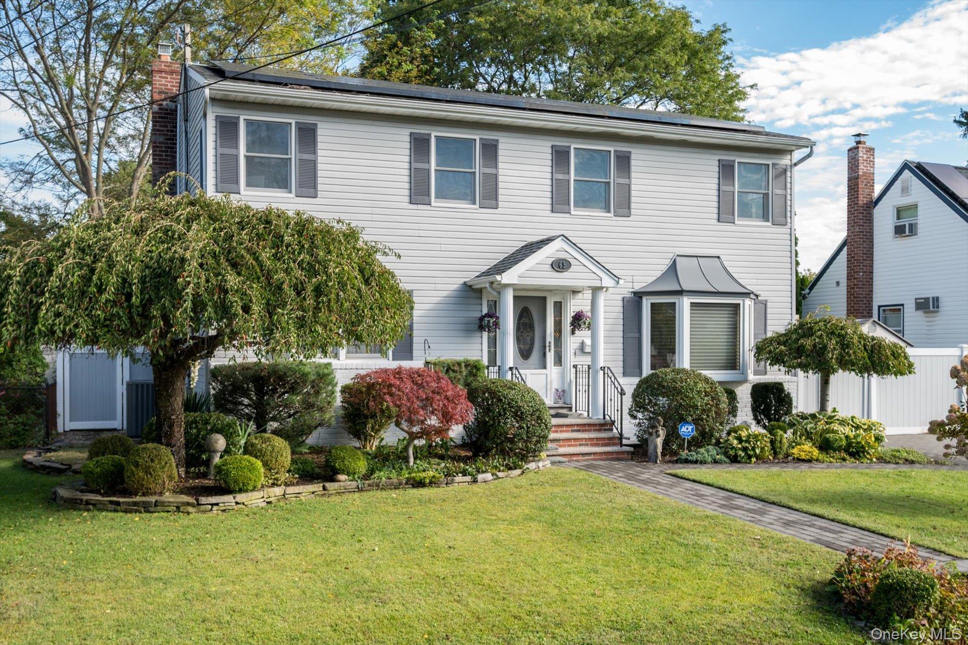 65 Harriet Road North Babylon, NY 11703 - Photo 3 of 31 Colonial house featuring a front lawn, a chimney, and roof mounted solar panels