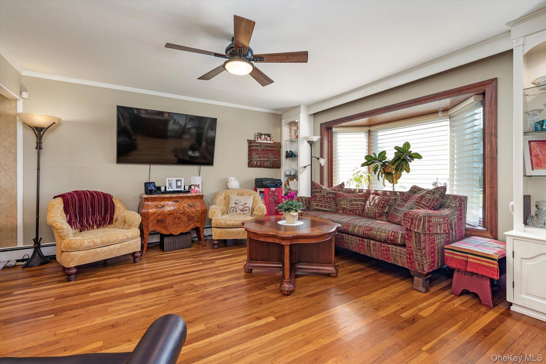 65 Harriet Road North Babylon, NY 11703 - Photo 5 of 31 Living room featuring ornamental molding, wood finished floors, and a ceiling fan