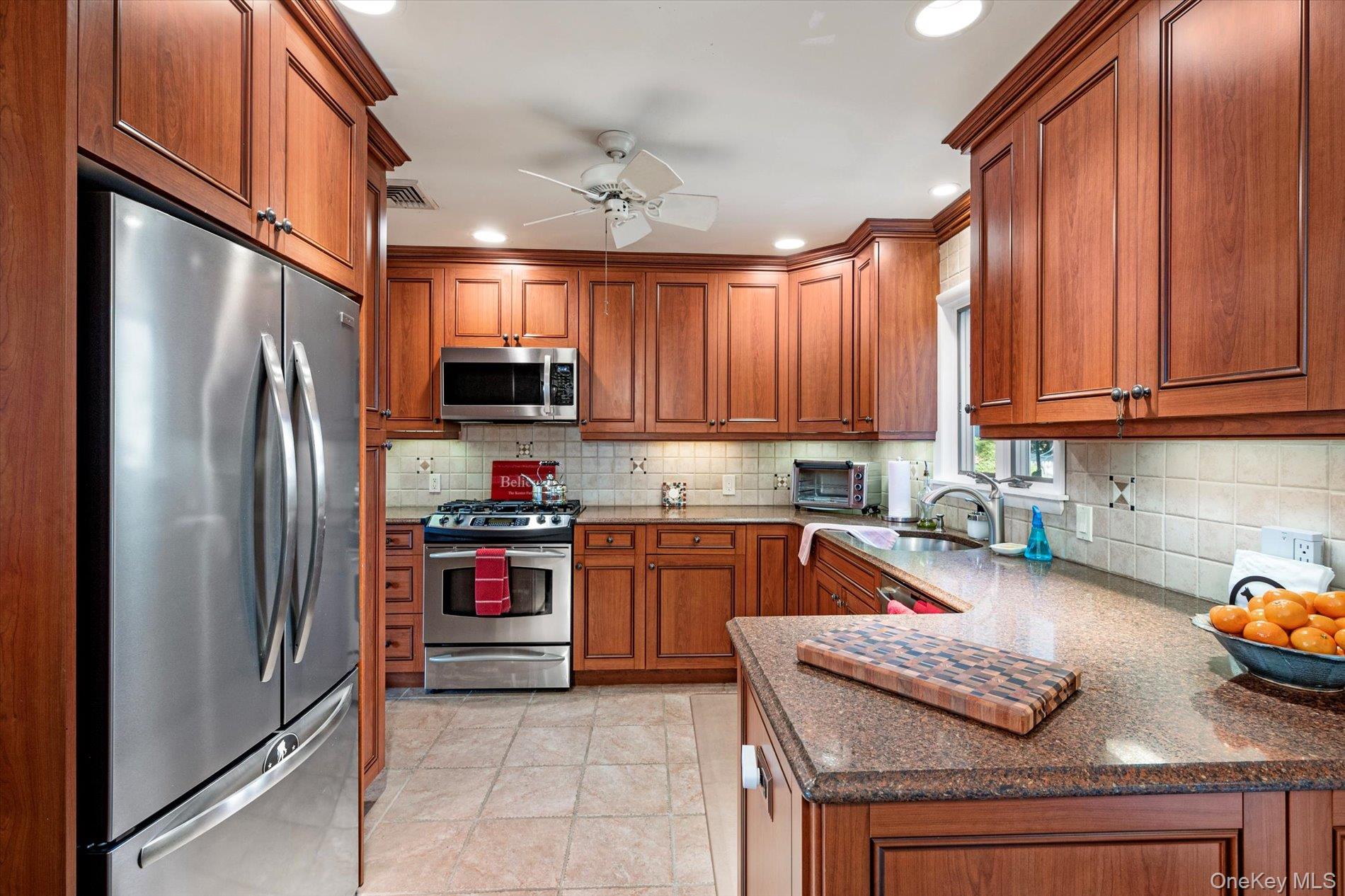 65 Harriet Road North Babylon, NY 11703 - Photo 8 of 31 Kitchen featuring brown cabinets, stainless steel appliances, recessed lighting, dark stone counters, and backsplash