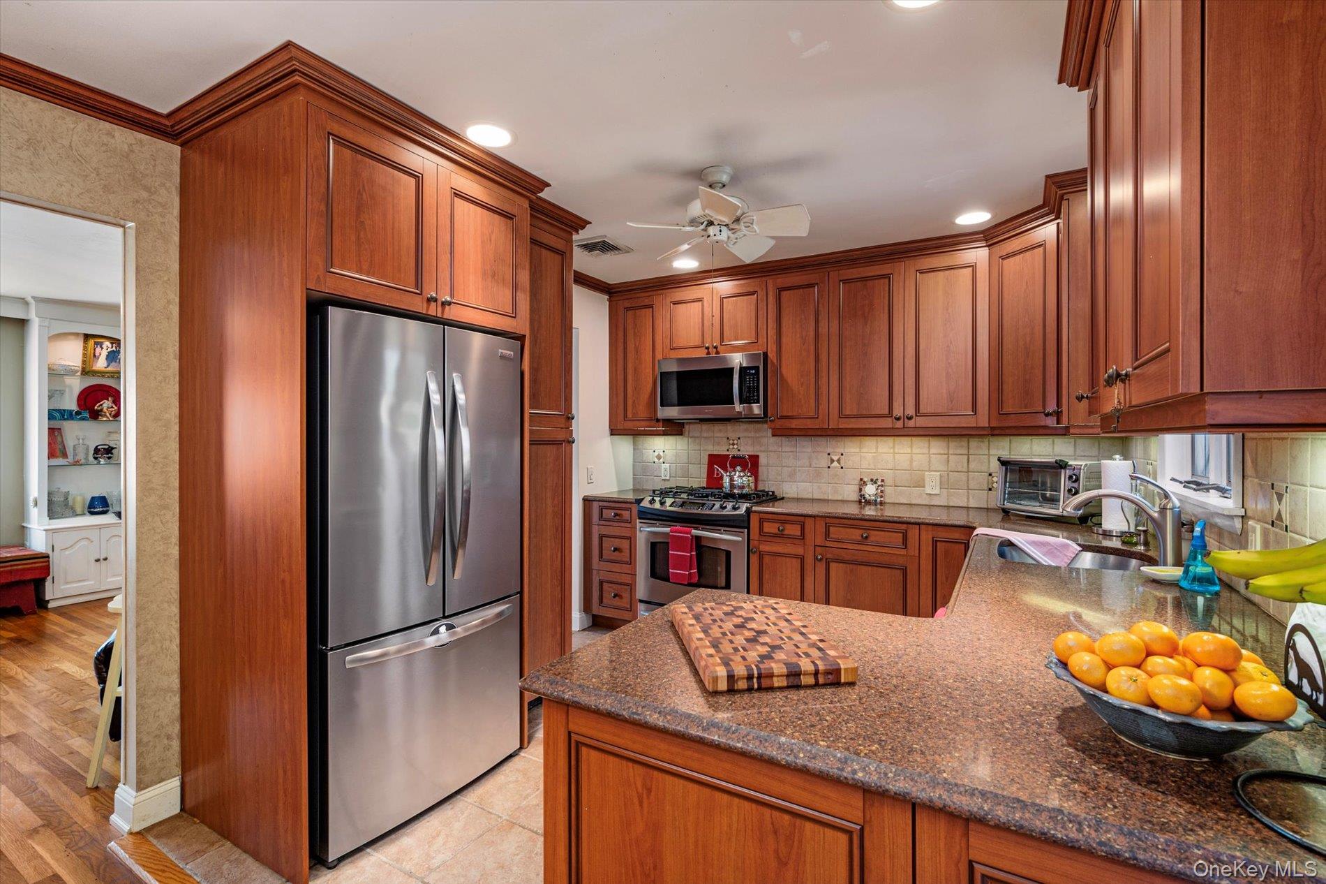 65 Harriet Road North Babylon, NY 11703 - Photo 9 of 31 Kitchen with brown cabinets, appliances with stainless steel finishes, dark stone countertops, backsplash, and recessed lighting