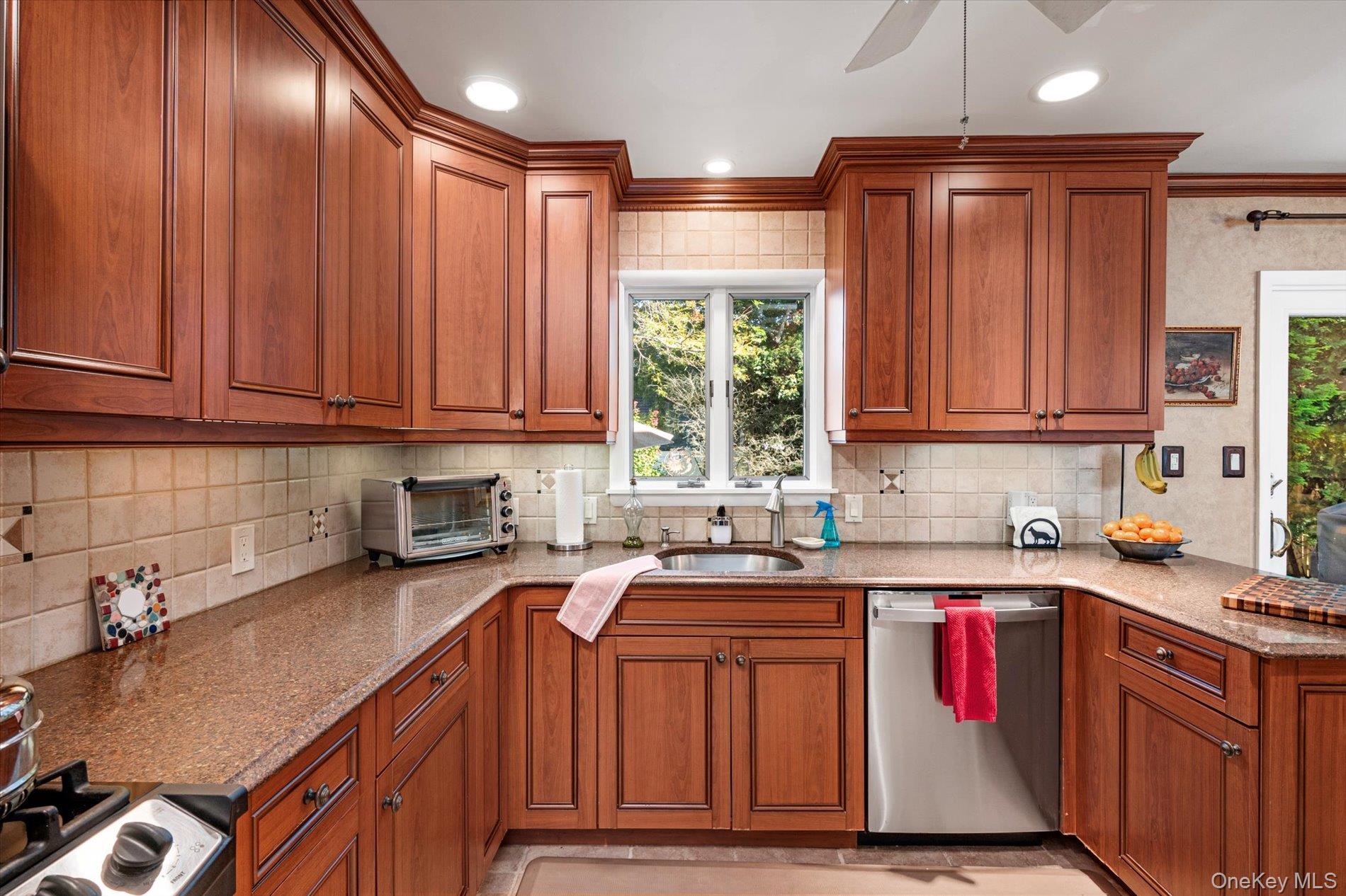 65 Harriet Road North Babylon, NY 11703 - Photo 10 of 31 Kitchen featuring brown cabinets, light stone counters, stainless steel appliances, ceiling fan, and backsplash