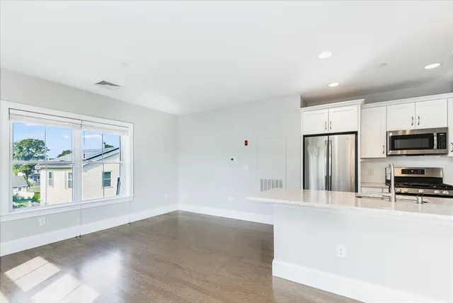 a large kitchen with stainless steel appliances a large counter top a stove and a refrigerator