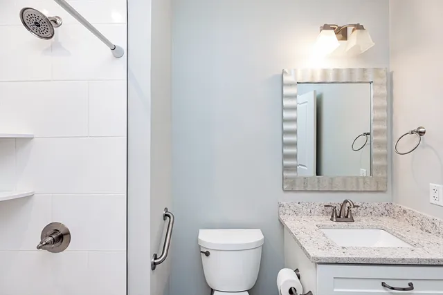 a bathroom with a granite countertop sink a toilet and a mirror