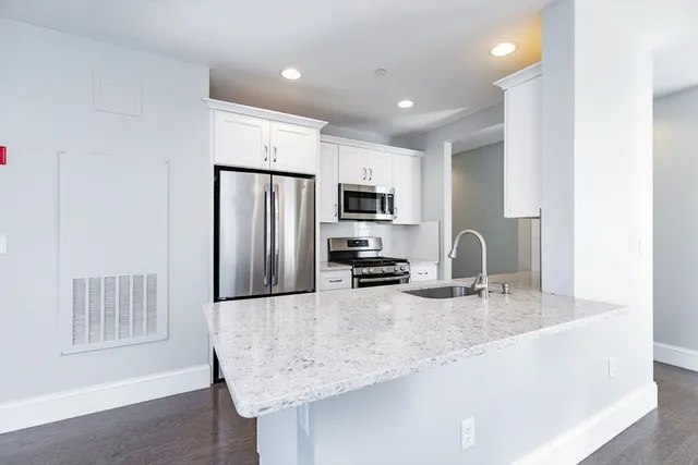 a kitchen with stainless steel appliances granite countertop a sink refrigerator and microwave