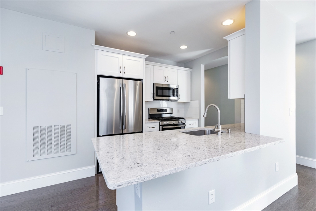 445 Essex Street, Unit 304 Swampscott, MA 01907 - Photo 7 of 35 a kitchen with stainless steel appliances granite countertop a sink refrigerator and microwave