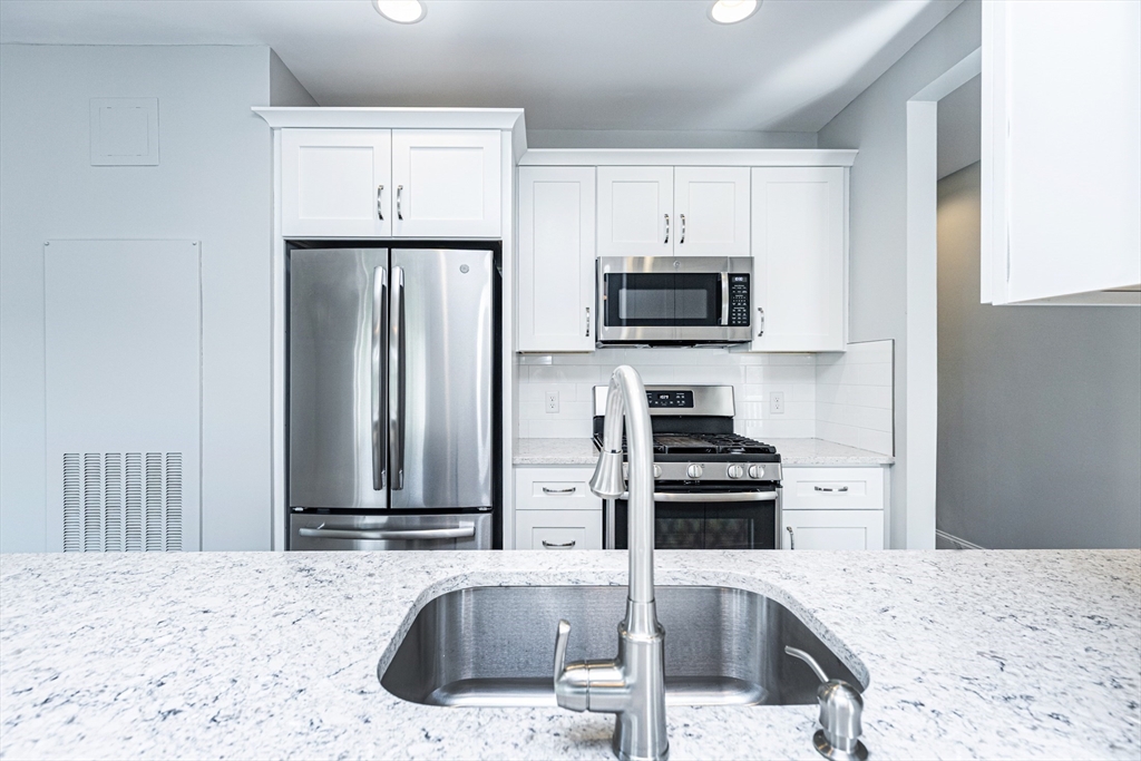 445 Essex Street, Unit 304 Swampscott, MA 01907 - Photo 9 of 35 a kitchen with kitchen island a sink stove and refrigerator