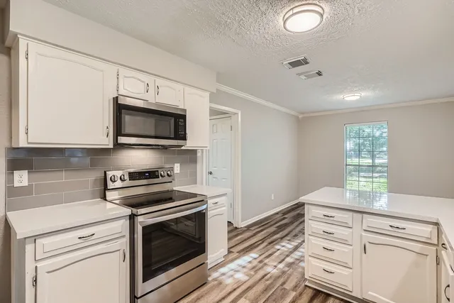 a kitchen with granite countertop white cabinets stainless steel appliances and window