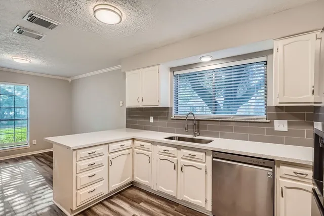 a kitchen with granite countertop a sink window and cabinets
