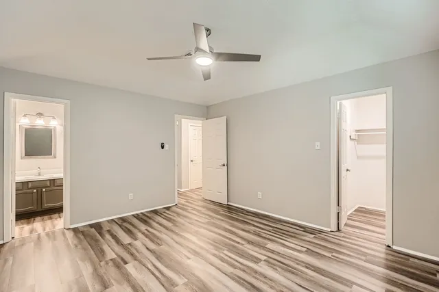 an empty room with wooden floor cabinet and windows