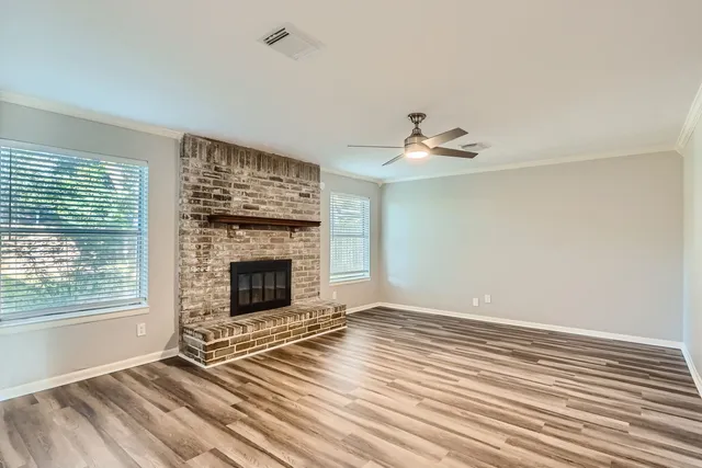 a view of an empty room with wooden floor fireplace and a window