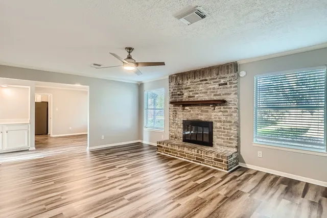 wooden floor fireplace and windows in an empty room
