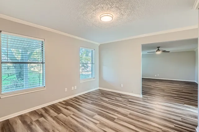 a view of an empty room with wooden floor and a window