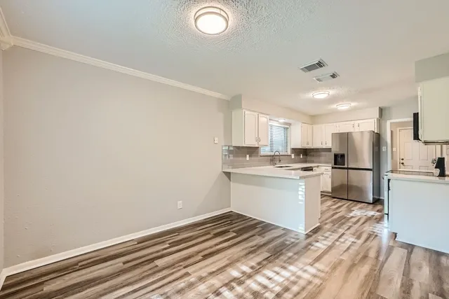 a kitchen with a refrigerator and white cabinets