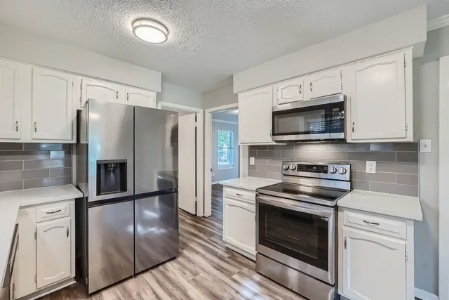 a kitchen with stainless steel appliances granite countertop a refrigerator stove and microwave