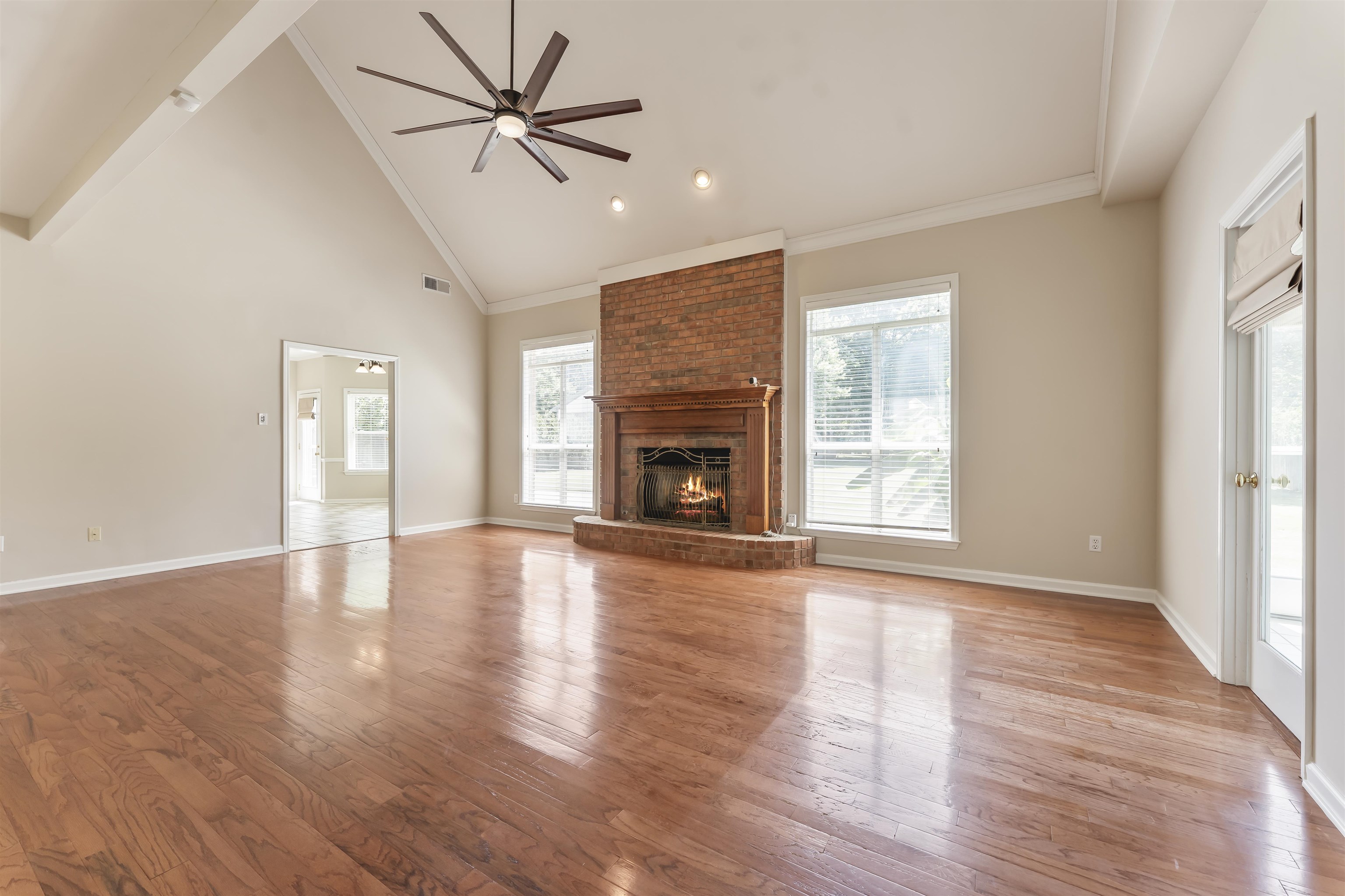 4279 High Plains Road Bartlett, TN 38135 - Photo 10 of 37 Spacious room featuring vaulted ceilings, wood-finish flooring, and a brick fireplace with a wood mantel