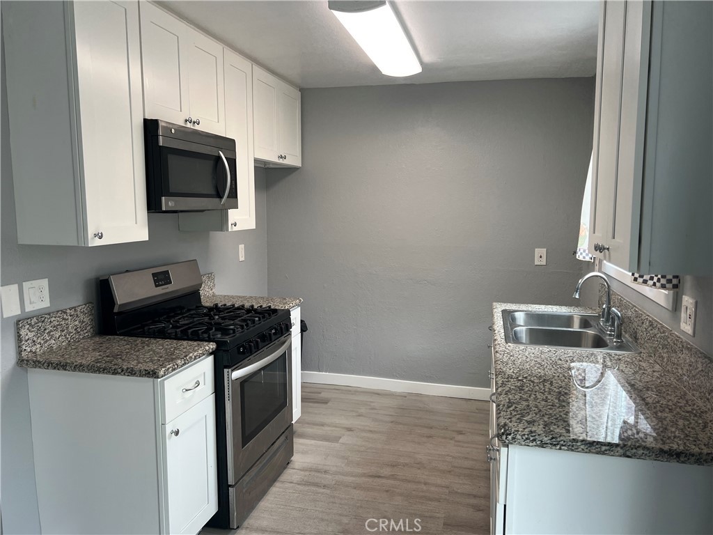 136 West 53rd Street, Unit A Long Beach, CA 90805 - Photo 6 of 13 a kitchen with stainless steel appliances granite countertop a sink stove and microwave