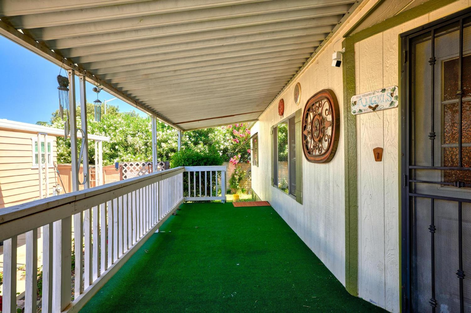 1200 South Carpenter Road, Unit 4 Modesto, CA 95351 - Photo 25 of 31 Covered porch featuring a security screen door, white railings, and green outdoor carpeting