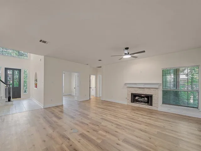 an empty room with wooden floor fireplace and a window