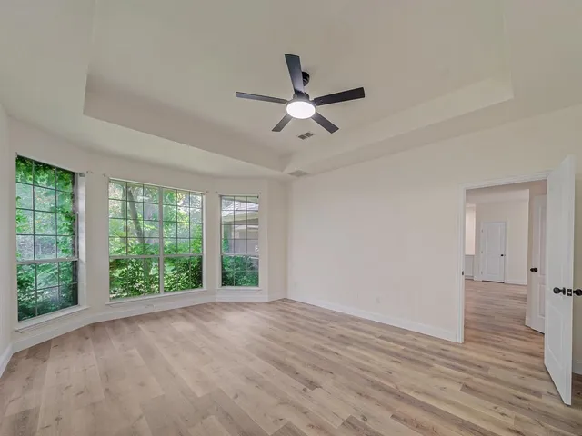 a view of n empty room with wooden floor and fan