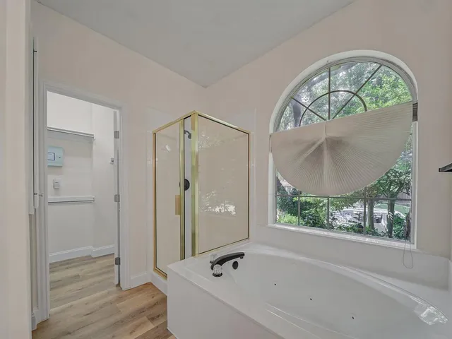 a bathroom with a tub a mirror and a shower