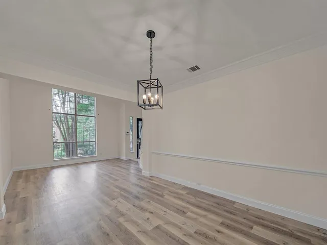 a view of a room with wooden floor a ceiling fan and windows