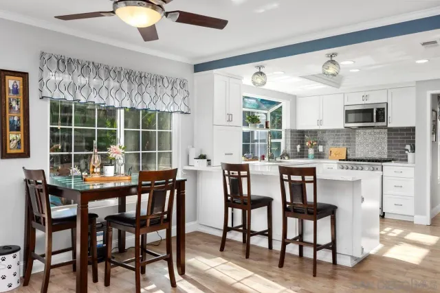 a kitchen with stainless steel appliances kitchen island granite countertop a table chairs sink and cabinets