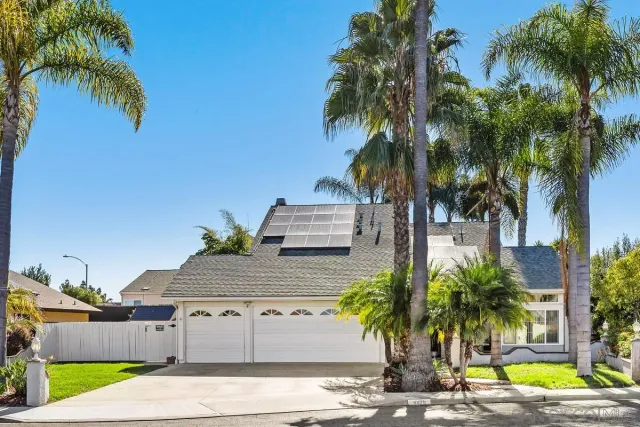 a view of a house with a yard and palm trees