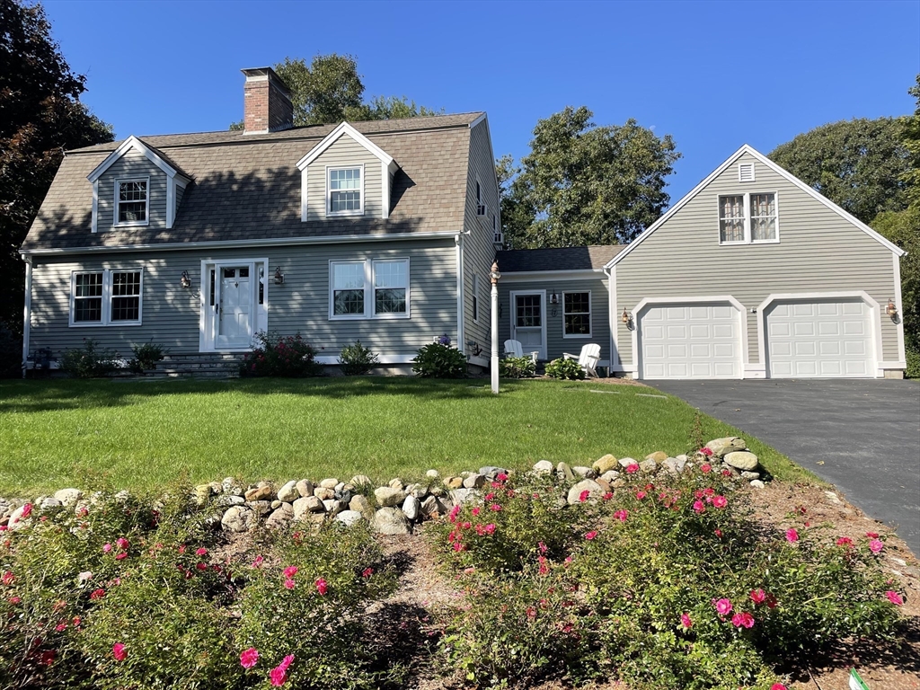 a front view of a house with a big yard and a garden