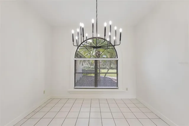 an empty room with chandelier fan and windows