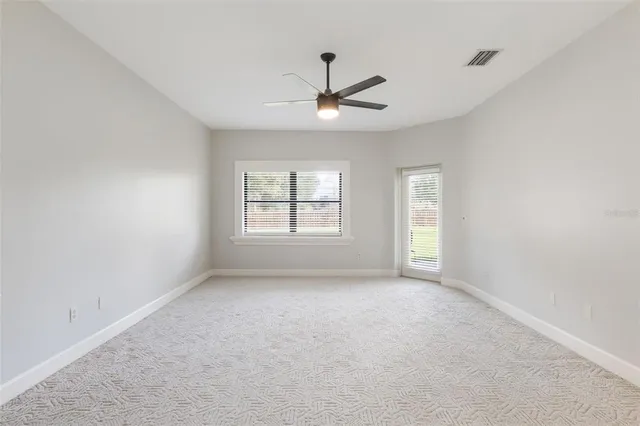 an empty room with a window and a fan