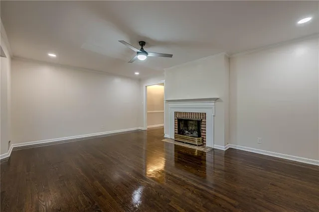 an empty room with wooden floor fireplace and fan