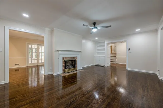 an empty room with wooden floor fireplace and windows