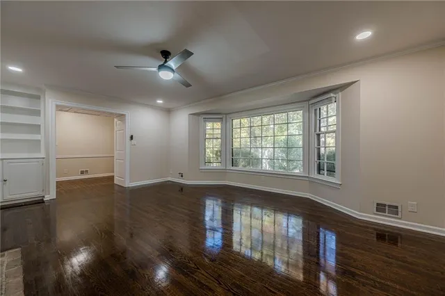 a view of an empty room with wooden floor and a window
