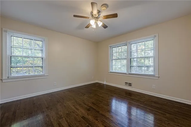 a view of an empty room with window and wooden floor