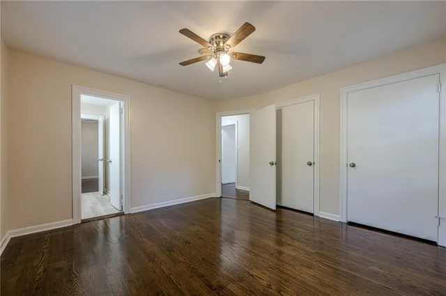 an empty room with wooden floor and ceiling fan