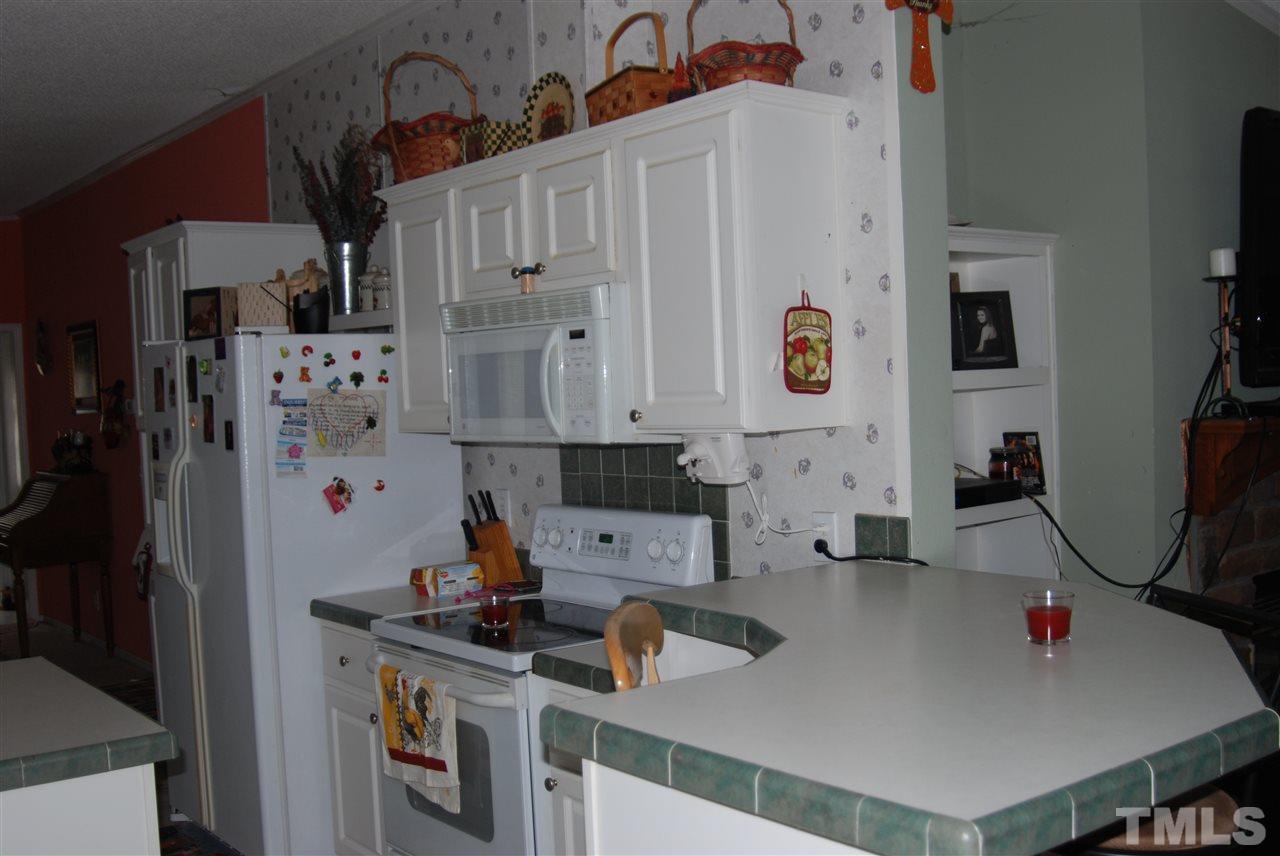 1298 O B J Road Dunn, NC 28334 - Photo 4 of 24 a kitchen with stainless steel appliances a refrigerator a sink and white cabinets