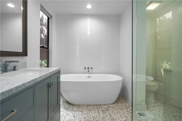 a bathroom with a granite countertop sink and mirror with bathtub