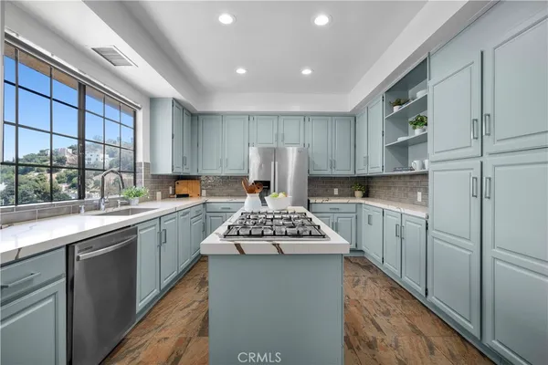 a kitchen with kitchen island stainless steel appliances a sink stove and cabinets