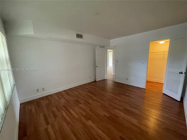 an empty room with wooden floor and windows