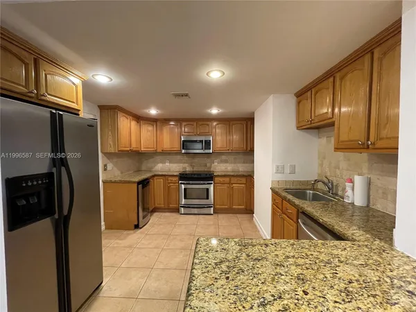 a kitchen with granite countertop a refrigerator and a stove top oven