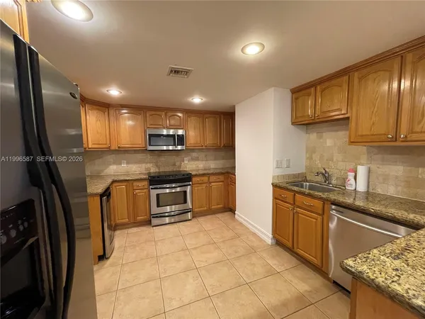a kitchen with stainless steel appliances granite countertop a refrigerator sink stove microwave and cabinets