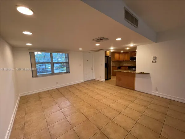 a view of empty room with kitchen and window