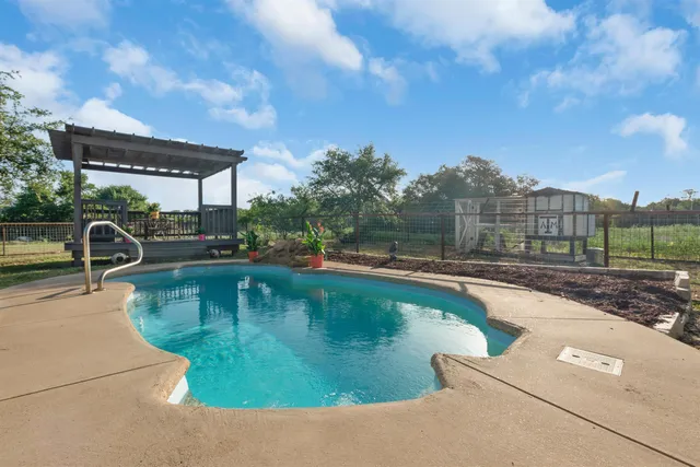 a view of a swimming pool and lounge chairs in back yard