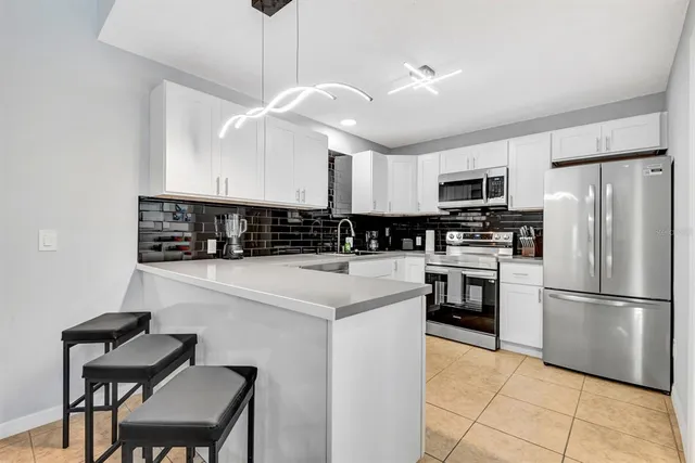 a kitchen with a refrigerator a microwave a stove and white cabinets